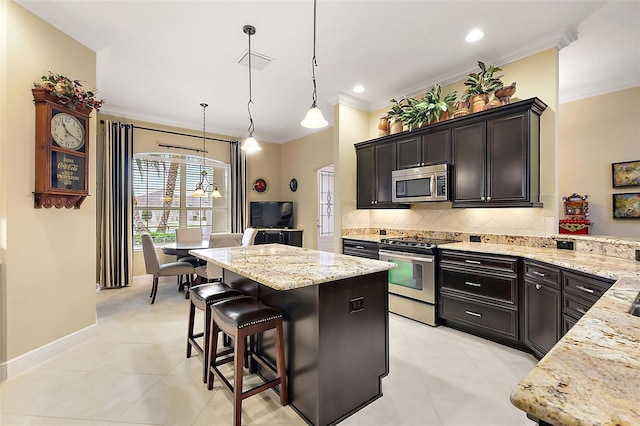 kitchen featuring light stone counters, a kitchen island, appliances with stainless steel finishes, decorative backsplash, and decorative light fixtures