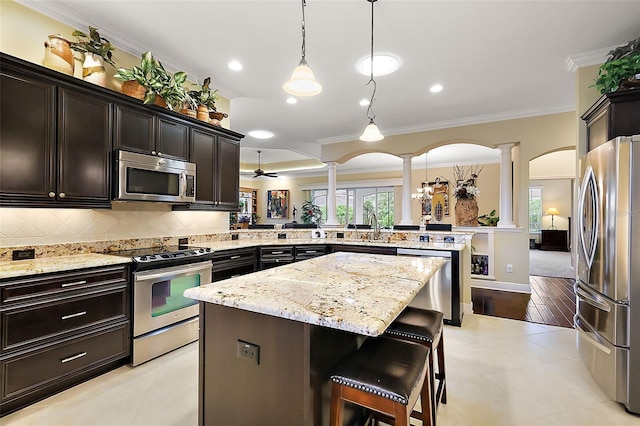 kitchen featuring decorative columns, a breakfast bar area, appliances with stainless steel finishes, a peninsula, and hanging light fixtures