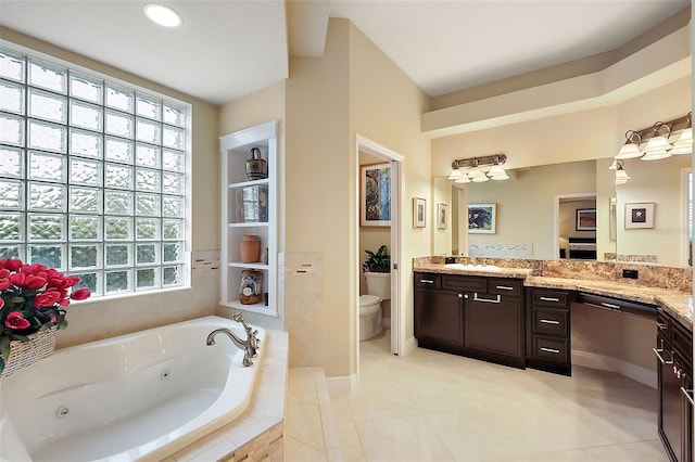 bathroom featuring a jetted tub, vanity, toilet, and a healthy amount of sunlight