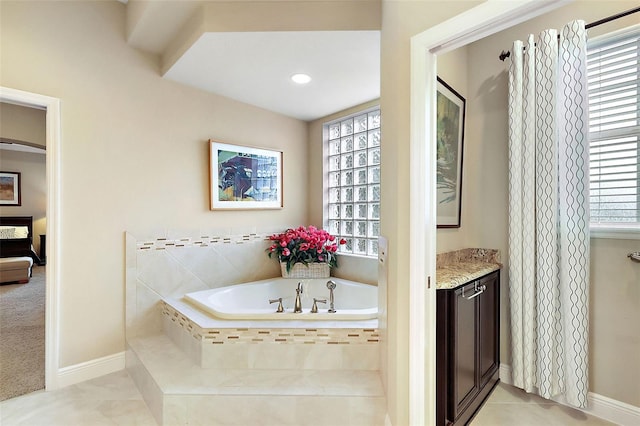 full bath with a healthy amount of sunlight, a garden tub, vanity, and tile patterned floors