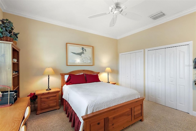 bedroom featuring visible vents, crown molding, light carpet, and two closets