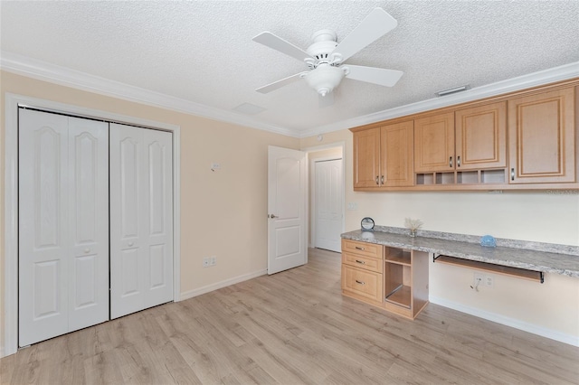 kitchen featuring built in desk, ornamental molding, light stone countertops, a textured ceiling, and light hardwood / wood-style flooring