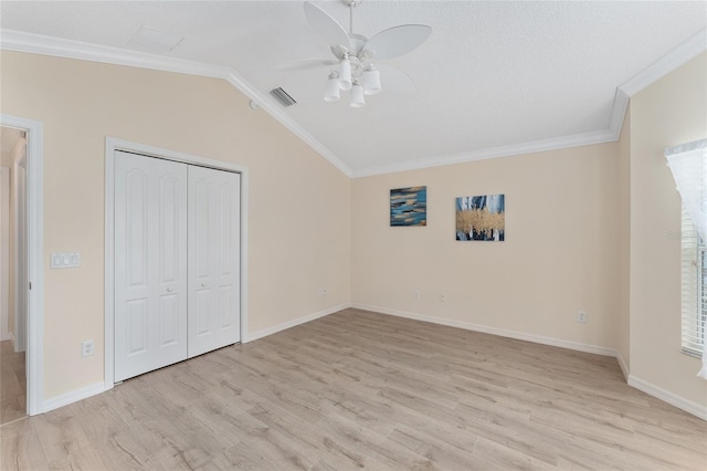 unfurnished bedroom featuring lofted ceiling, crown molding, ceiling fan, a closet, and light wood-type flooring