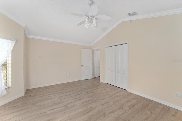 unfurnished bedroom with lofted ceiling, crown molding, light hardwood / wood-style flooring, ceiling fan, and a closet