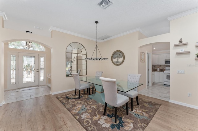 dining area featuring ornamental molding, a textured ceiling, and light hardwood / wood-style floors