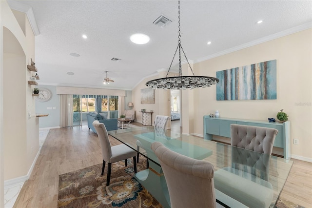 dining room featuring crown molding, a textured ceiling, and light wood-type flooring