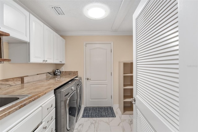 laundry area with cabinets, ornamental molding, washer and clothes dryer, and a textured ceiling