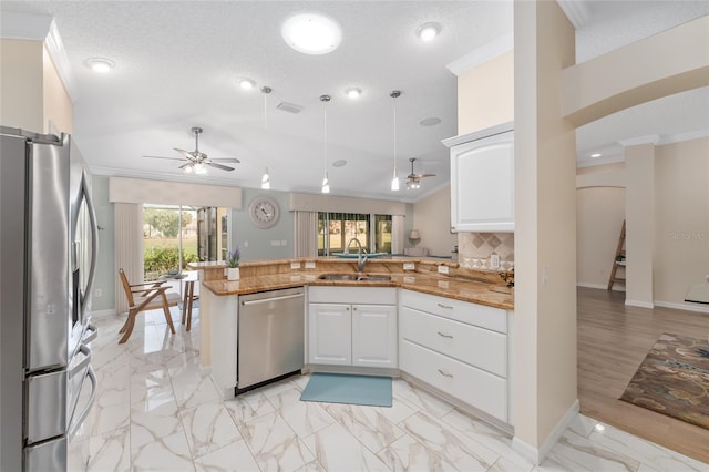 kitchen with sink, crown molding, kitchen peninsula, stainless steel appliances, and white cabinets