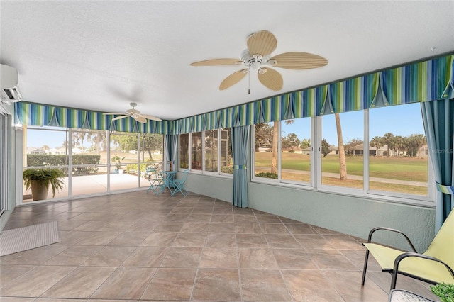 unfurnished sunroom featuring ceiling fan, a wall mounted AC, and a healthy amount of sunlight