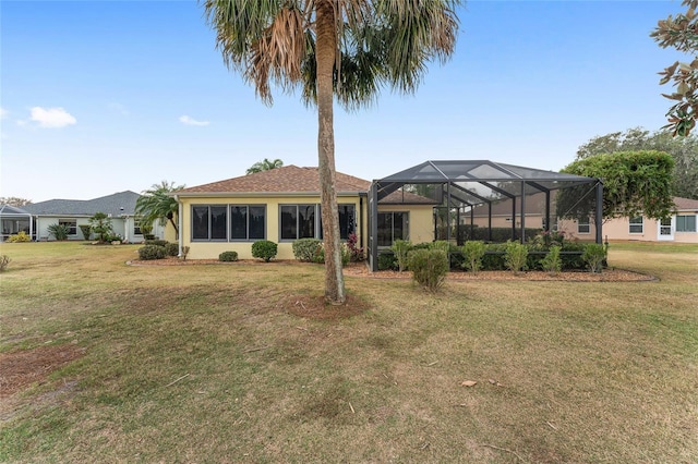 rear view of property featuring glass enclosure and a lawn