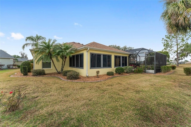 rear view of house featuring a lanai and a lawn