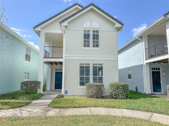 view of front of property with a balcony and a front lawn