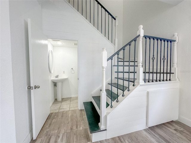 staircase featuring sink, hardwood / wood-style floors, and a high ceiling