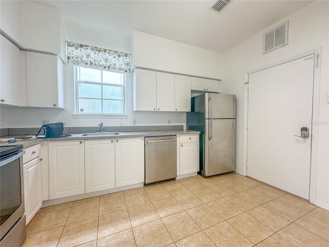 kitchen with sink, stainless steel appliances, white cabinets, and light tile patterned flooring