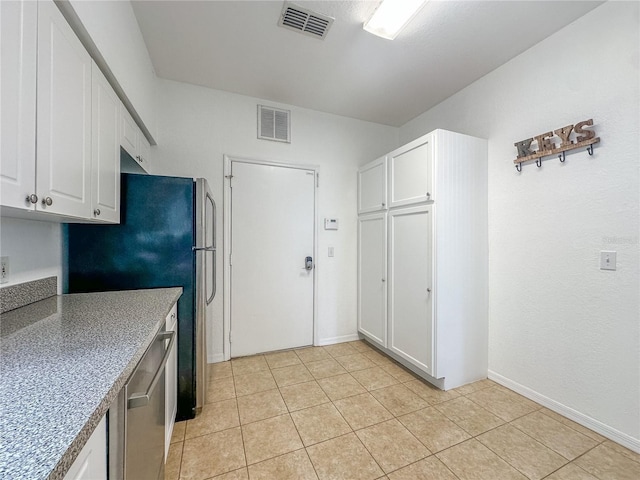 kitchen featuring light tile patterned flooring, white cabinets, and appliances with stainless steel finishes