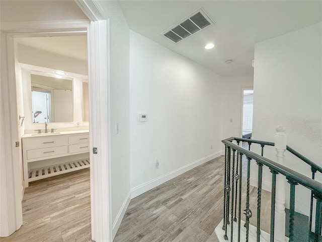 hallway with sink and light hardwood / wood-style flooring