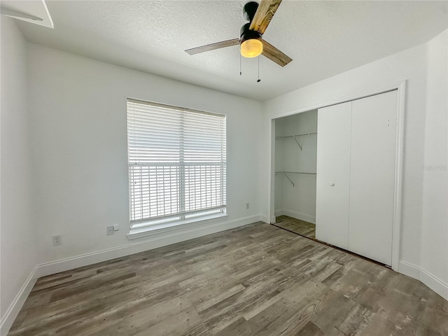 unfurnished bedroom featuring ceiling fan, wood-type flooring, a closet, and a textured ceiling