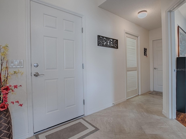 entrance foyer with a textured ceiling and baseboards