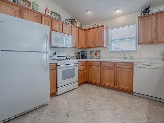 kitchen with a textured ceiling, lofted ceiling, white appliances, a sink, and light countertops