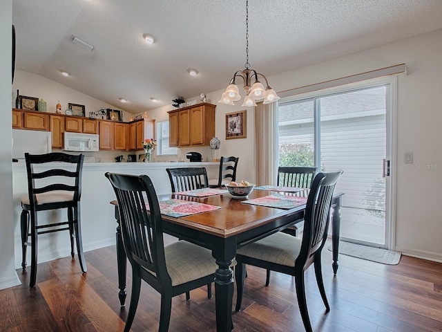 dining space with lofted ceiling, a textured ceiling, and dark wood finished floors