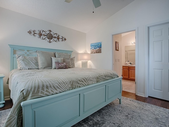 bedroom with lofted ceiling, ceiling fan, a textured ceiling, dark wood finished floors, and ensuite bath