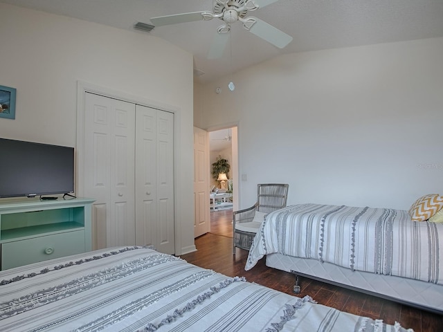 bedroom with dark wood-style floors, a closet, visible vents, vaulted ceiling, and ceiling fan