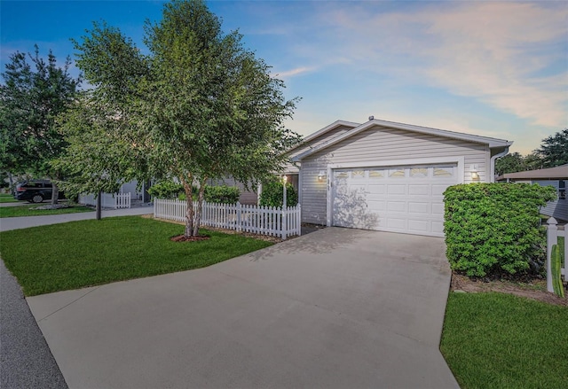 ranch-style home with a yard, concrete driveway, and fence