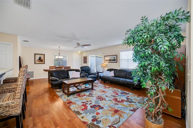 living area with a textured ceiling, wood finished floors, and visible vents