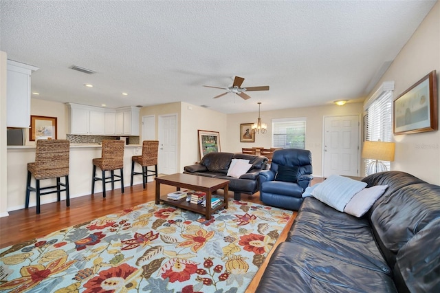 living area featuring visible vents, wood finished floors, a textured ceiling, a notable chandelier, and recessed lighting