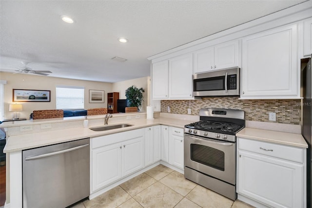 kitchen featuring stainless steel appliances, light countertops, a sink, and a peninsula