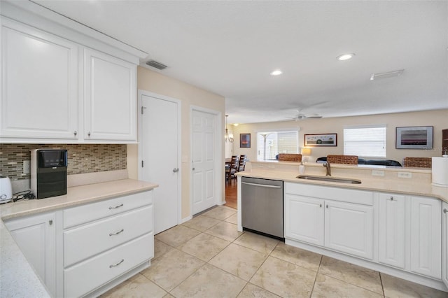 kitchen featuring visible vents, white cabinetry, light countertops, stainless steel dishwasher, and backsplash