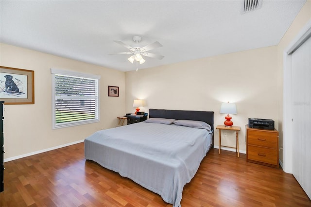 bedroom featuring baseboards, visible vents, ceiling fan, and wood finished floors