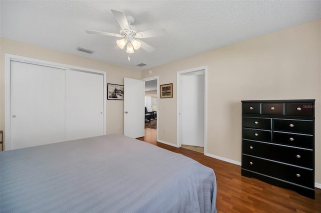 bedroom with a textured ceiling, dark wood-type flooring, visible vents, and a ceiling fan