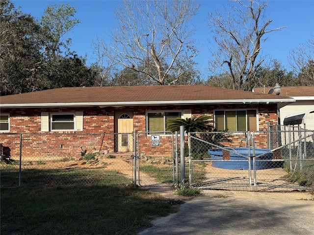 ranch-style house featuring brick siding, a fenced front yard, and a gate