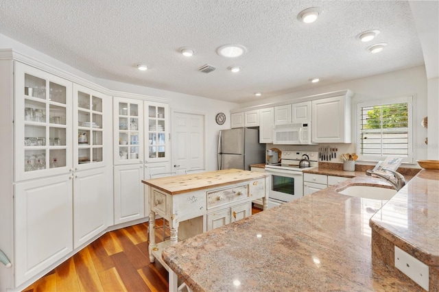 kitchen featuring white appliances, a sink, white cabinetry, light wood-style floors, and wooden counters