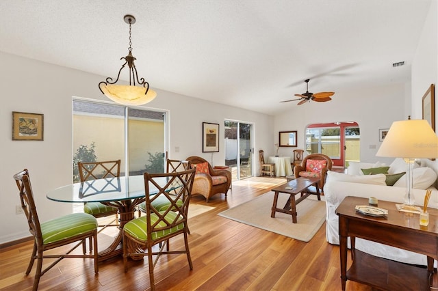 dining room featuring lofted ceiling, light wood-style floors, ceiling fan, and visible vents