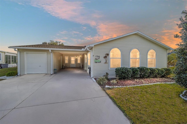 ranch-style house featuring a carport, a garage, and a yard