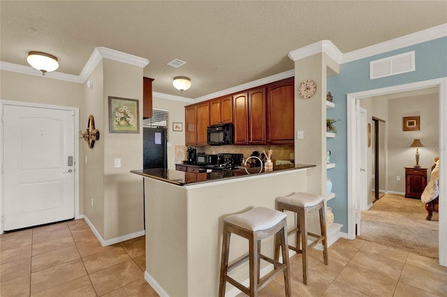 kitchen featuring crown molding, kitchen peninsula, light tile patterned floors, and black appliances