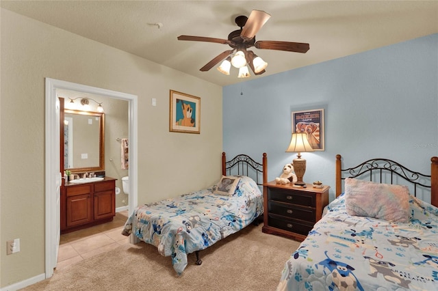 bedroom with ceiling fan, ensuite bath, sink, and light carpet