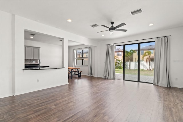 unfurnished living room featuring dark wood-type flooring, a wealth of natural light, and ceiling fan