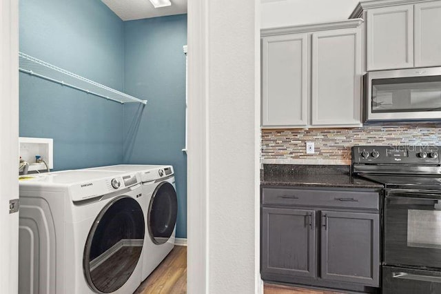 washroom with washing machine and clothes dryer and light hardwood / wood-style flooring