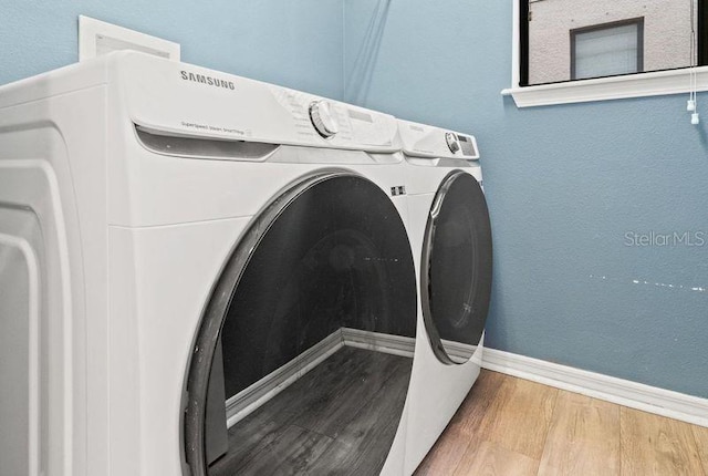 washroom with hardwood / wood-style flooring and washing machine and dryer