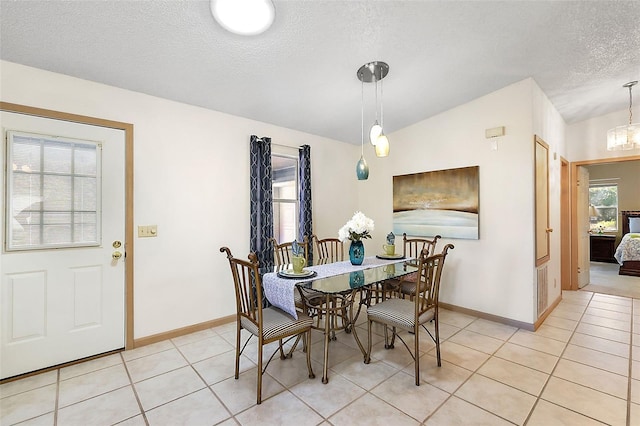 tiled dining space featuring vaulted ceiling and a textured ceiling