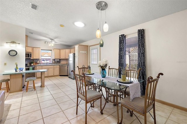 dining space with sink, vaulted ceiling, a textured ceiling, and light tile patterned floors