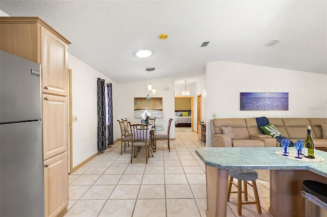 dining room featuring light tile patterned floors, vaulted ceiling, and a textured ceiling