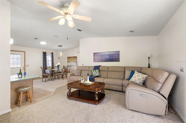 tiled living room featuring lofted ceiling, ceiling fan, and a textured ceiling