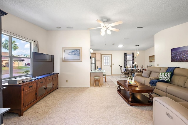 living room with ceiling fan, vaulted ceiling, light carpet, and a textured ceiling