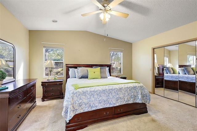 bedroom with vaulted ceiling, a textured ceiling, a closet, and light colored carpet