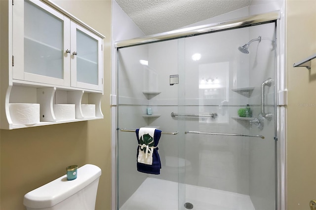 bathroom featuring a textured ceiling, toilet, and a shower with shower door