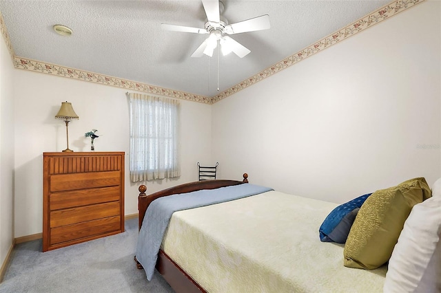 bedroom with ceiling fan, light carpet, and a textured ceiling